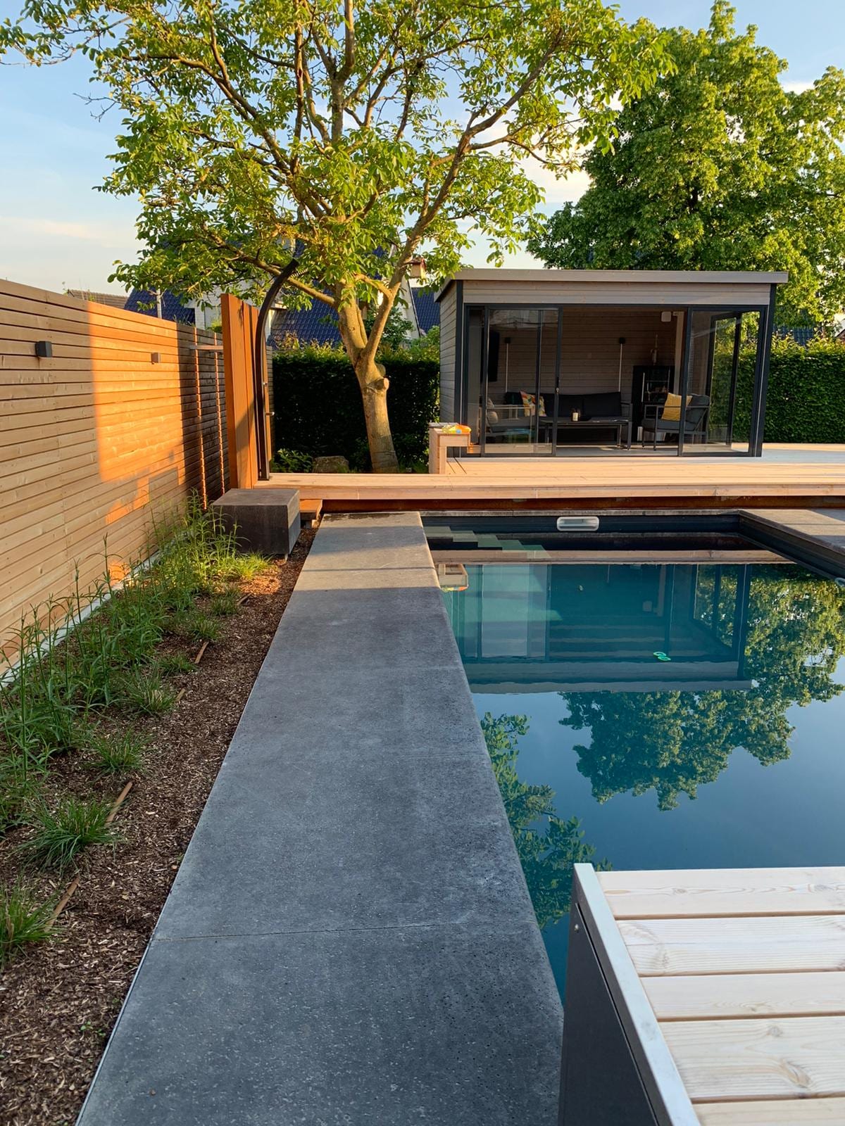 Klassischer Pool mit Natursteineinfassung, Holzdeck und Gartenpavillon